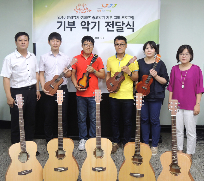 낙원악기상가 번영회 유강호 회장(사진좌측)과 악기를 기부 받는 센터 관계자 4인(사진중앙) 및 사회복지법인 '함께걷는아이들' 유원선 사무국장(사진우측)