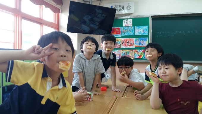 1일 울산의 모 초등학교 돌봄교실 학생들이 사회적경제개발원이 지급한 간식을 먹으며 기념사진을 촬영하고 있다. (사진제공=사회적경제개발원)