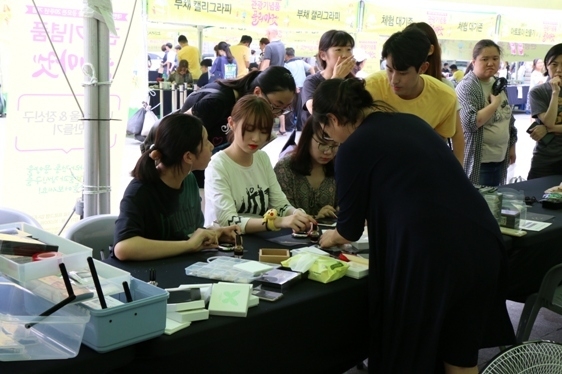 지난 7월 광화문 중앙광장에서 열린 관광기념품 플리마켓 방문객이 관광기념품을 만드는 체험을 하고 있다